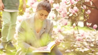 Bahar günü, anne ve oğul ergen manolya çiçeğinin arka planında. Doğada piknik, anneler günü.
