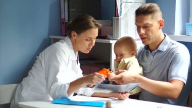 Babasıyla birlikte çocuk doktoruyla randevusu olan küçük bir çocuk. Doktor reçete yazar, çocuk oyuncakla oynar.