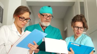 Olgun erkek doktor ve iki genç bayan doktor genel bir tıbbi tavsiyede bulunuyorlar. İşte üç doktor, klinikte tıbbi personel.