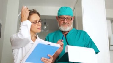 Hoş bir çift, iki doktor, bir adam ve bir kadın ellerinde dosyalar, çerçeveye bak ve gülümse. Uluslararası Doktorlar Günü
