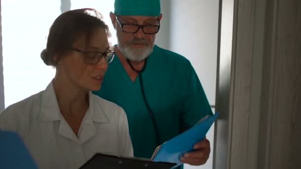 Kvinnlig läkare och en manlig assistent går ner i korridoren till ett möte. Medicinsk personal arbetar på kliniken. Medicin och hälsovård — Stockvideo