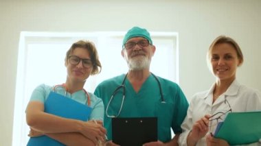 Üç gülen tıbbi personel. Erkek doktor ve iki sağlık görevlisi. Tıp ve sağlık hizmetleri kavramı