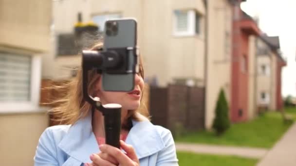 Piękna dziewczyna nagrywa filmy do swoich blogów za pomocą smartfona i stabilizatora. Blogi wideo. Vlogger z kamerą komórkową stabilizator nagrywania na zewnątrz wideo blog — Wideo stockowe