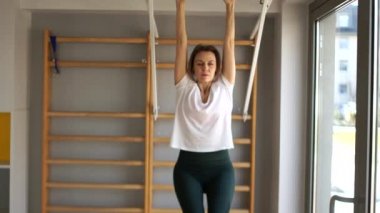 Kız yatay çubukta basın egzersizleri yapıyor, bacaklarını öne doğru kaldırıyor. Spor Spor Karantinası