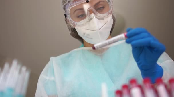 Retrato de una asistente de laboratorio en un laboratorio de ciencias con una muestra de sangre para investigación en probeta. Pruebas poblacionales del coronavirus covid-19 — Vídeos de Stock