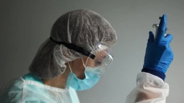 Mikrobiyolog laboratuvarda Coronavirus Covid-19 virüsü bulaşmış kan örnekleri üzerinde çalışıyor. Koruyucu kıyafetli bir laboratuvar asistanının elinde boru dağıtıcı.