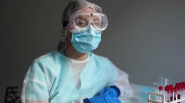 Sars-Cov-2 teşhisi, Coronavirus covid-19. Yorgun bir laboratuar teknisyeninin portresini, masasında üzgün gözlerle test tüpleri, tıbbi örnekler ve reaksiyonlarla kapatın.