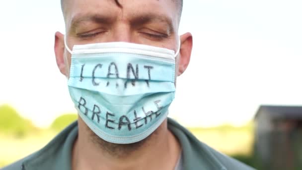 Protestas masivas contra la brutalidad y la violencia policial. Joven hombre blanco con una máscara con la inscripción que no puedo respirar. BlackLivesMatter — Vídeo de stock