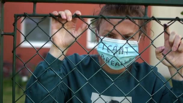 Young white woman behind bars with the inscription on the mask. I cant breathe. Knocks on the fence, aggression look. Protests and riots, reaction to the death of George Floyd in Mineapolis — Stock Video