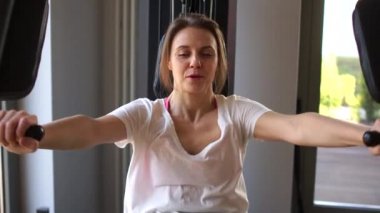 Normal spor, karantina sporu, spor salonu, sağlıklı yaşam tarzı, yakın portreler. El ve omuz egzersizleri. Güzel sarışın kız ellerini sakız makinesine sokuyor.