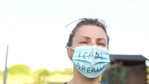 Retrato cercano de una joven mujer blanca con una máscara con la inscripción No puedo respirar. Protestas masivas contra el racismo en el mundo — Vídeo de stock