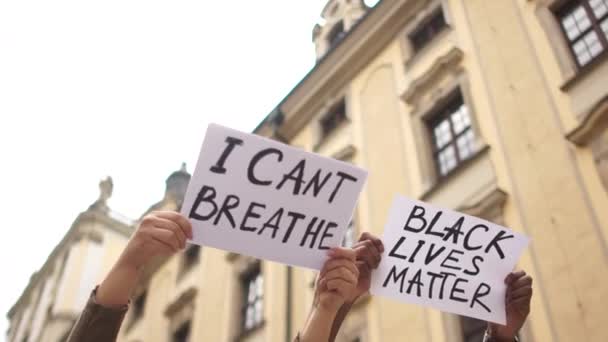 Protestos contra o racismo e a discriminação nos EUA e na Europa. Jovem homem africano e mulher caucasiana segurando cartazes de papelão com o texto da mensagem I CANT BREATHE and BLACK LIVES MATTER — Vídeo de Stock