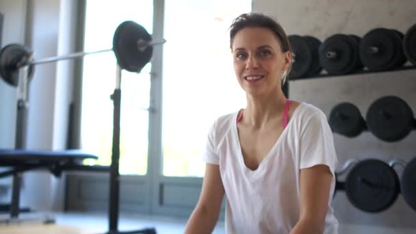 Retrato de una joven sonriente en el gimnasio sentada en posición de loto. Yoga y deportes regulares — Vídeos de Stock