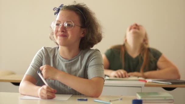 Ευτυχισμένα παιδιά, δύο έφηβα κορίτσια στην τάξη, να κάνουν σχολικές εργασίες. Μαθήτριες στην τάξη γελάνε, πίσω στο σχολείο. — Αρχείο Βίντεο