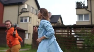 Kız operatör akıllı telefon ve dengeleyici kullanarak çalışan bir modelin videosunu çekiyor. İki kız bir blog için açık hava videosu çekiyor. Hareket halindeki video günlüğü için dinamik çekim