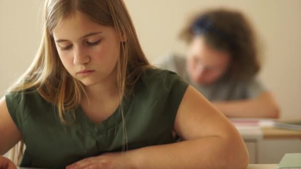 Nära porträtt av tonårstjej som sitter i skolan vid sitt skrivbord. Skolflicka räcker upp handen, tillbaka till skolan — Stockvideo