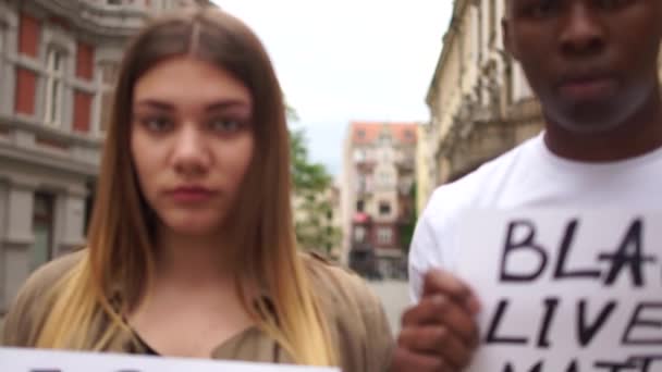 Protesty przeciwko rasizmowi i dyskryminacji w USA i Europie. Młody Afrykanin mężczyzna i biała kobieta trzymając kartonowe plakaty z tekstem wiadomości I CANT BREATHE and BLACK LIVES MatTER — Wideo stockowe