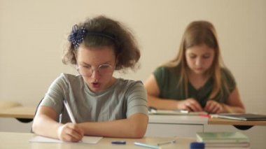 Sınıftaki çocuklar son bir kontrol testi yazıyorlar. Arka masadan bir kız sınıf arkadaşının dikkatini dağıtıyor. Liseli kız kızgın, okula geri döndü.