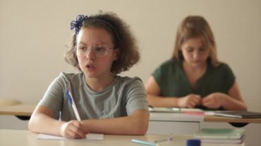 Arka masadan bir kız sınıf arkadaşının dikkatini dağıtıyor. Liseli kız kızgın, okula geri döndü. Sınıftaki çocuklar son bir kontrol testi yazıyorlar.