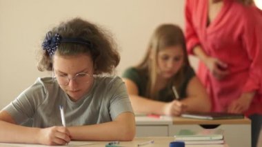 Liseli kızlar ders sırasında kavga ederler. Sınıf arkadaşı başka bir öğrenciye bir parça kağıt fırlatıyor. Okul zorbalığı