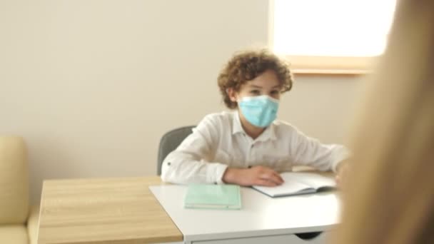 Bambini in maschere protettive a scuola in una lezione. Scuola post quarantena, nuova normalità, nuove regole, distanza sociale — Video Stock