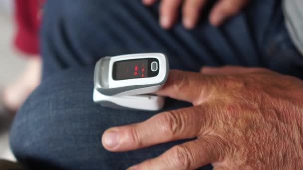 Pulsoximeter an der Hand eines älteren Mannes. Überwachung des Sauerstoffgehalts im Blut eines Patienten mit Lungenentzündung, Coronavirus covid-19 — Stockvideo