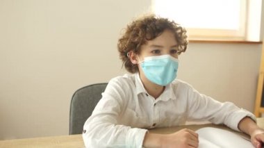 Koruyucu maskeli kıvırcık okul çocuğu sınıf arkadaşından kalem istiyor. Karantina sonrası okul, yeni kurallar, sosyal mesafe