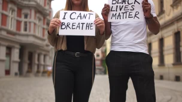Uczniowie, czarny chłopiec i biała dziewczyna trzymają tabliczki z napisami w rękach. Nie mogę oddychać, a czarne życie ma znaczenie. Masowe protesty w USA i Europie przeciwko przemocy i rasizmowi — Wideo stockowe