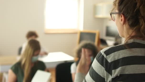 El profesor en el aula explica un nuevo tema a los estudiantes. Niños enmascarados, vida post-cuarentena, nueva normalidad después del cierre, coronavirus covid-19. Regreso a la escuela — Vídeos de Stock