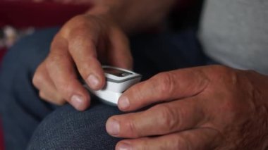 Emekli adam, Coronavirus covid-19 salgını sırasında taşınabilir nabız oksimetresi kullanarak kandaki oksijen seviyesini bağımsız olarak ölçer.