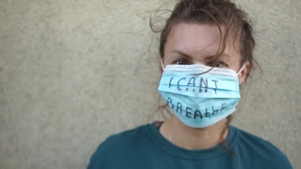 Retrato cercano de una mujer joven con una máscara médica con la inscripción No puedo respirar en el fondo de la pared. Las vidas de los negros importan, apoyando protestas contra la violencia y el racismo — Vídeo de stock