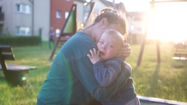 Een jongen huilt. Een moeder knuffelt hem. Onderwijs, ouderschap concept, moederdag. Portretten van een kleine mooie jongen met zijn moeder buiten — Stockvideo