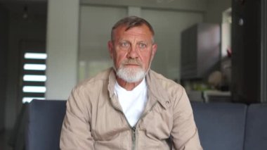 Yoksulluk ve işsizlik kavramı. Sakallı olgun bir adam kanepede oturuyor. Üzgün depresif bir adamın portresi. Dünya ekonomik krizi, azalan gelir