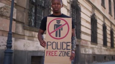 Postersiz polis bölgesi olan genç bir siyahın açık hava portresi. Afrikalı Amerikalı öğrenci polis şiddetini ve ırkçılığı protesto etti