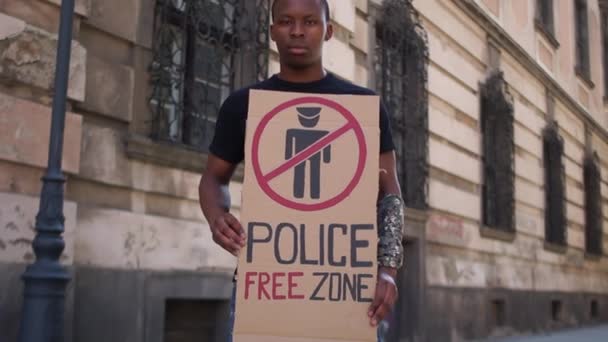ポスター警察の無料ゾーンを持つ若い黒人男性の屋外肖像画。アフリカ系アメリカ人学生が警察の暴力や人種差別に抗議 — ストック動画