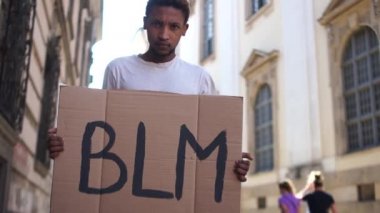Afro-Amerikalı bir adam elinde BLM yazılı bir poster tutuyor. Siyahi yaşamların hareketini destekleme eylemi önemlidir. ABD 'de ırkçılık ve şiddete karşı toplu protestolar