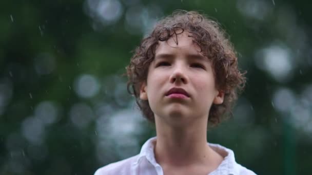 Blízký portrét smutného kudrnatého teenagera stojí v lijáku. Psychologické problémy konceptu dospívání — Stock video