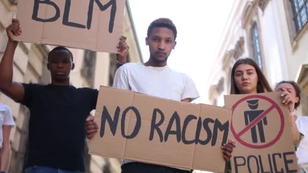 Un grupo multirracial de estudiantes protesta contra el racismo. Niños y niñas llevan pancartas con las palabras: no hay racismo, la vida de los negros importa, la zona libre de la policía — Vídeo de stock