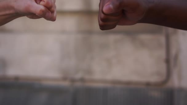 Feche um punho preto e um punho branco chocou em um clinch contra uma parede. Sem racismo, tolerância e politicamente correto na sociedade. Protestos dos EUA — Vídeo de Stock