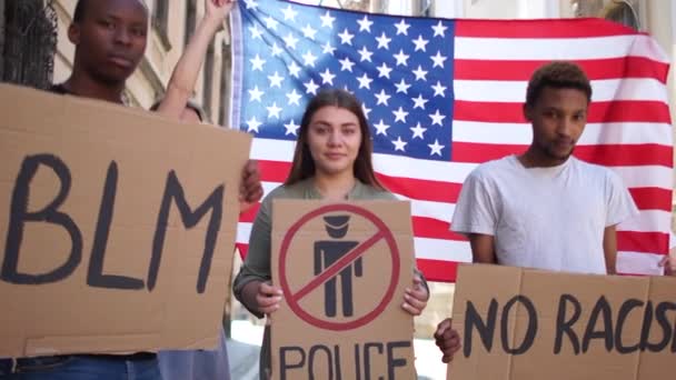 Protesta pacífica de Black Lives Matter. Un grupo juvenil interracial protesta por la violencia y el racismo. Hombres negros y mujeres blancas sostienen en sus manos carteles con las palabras no racismo, BLM, zona libre de la policía — Vídeo de stock