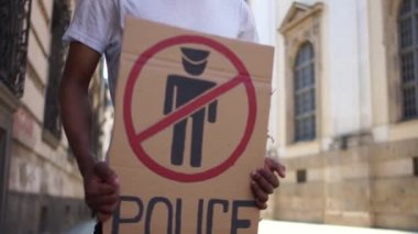 Beyaz tişörtlü siyah bir öğrenci şehrin ortasında dikiliyor. Afro-Amerikalı bir adam, üzerinde POLİSE serbest bölgesi yazan bir pankart tutuyor. Polis şiddetine karşı protestolar