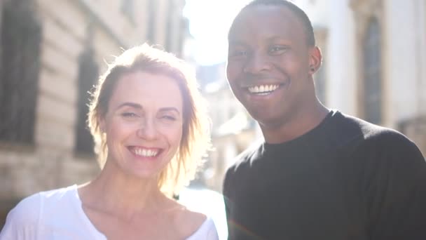 Close outdoor portrait of a happy man and woman. A black guy and a white girl are smiling. Black and white couple in love, sun rays — Stock Video