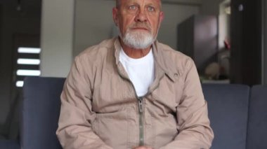 Gri sakallı bir adam üzgün bir yüzle kanepede oturur. İşten çıkarılan işçiler gelecek, işsizlik ve ekonomik kriz konsepti hakkında endişeli