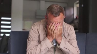 Olgun bir adamın Indore portresi kanepede oturuyor ve elleriyle yüzünü örtüyor. İşsizlik ve Coronavirus covid-19 karantinasından sonraki ekonomik kriz nedeniyle depresyon