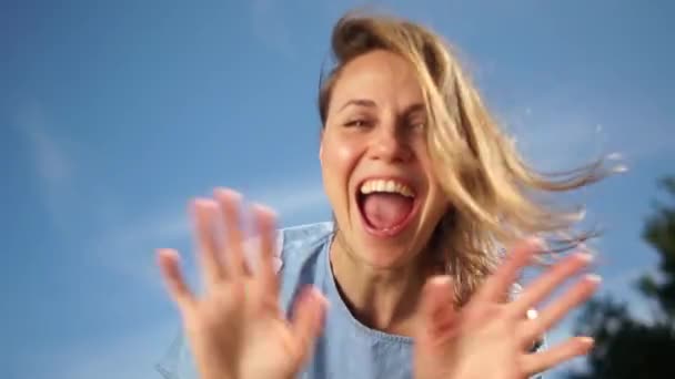 Retrato de una joven mujer atractiva sonriente vestida con jeans en un día soleado sobre el fondo azul del cielo. Mujer feliz — Vídeo de stock