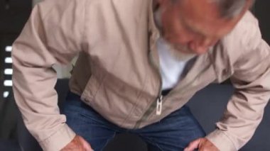 Üzgün, gri saçlı bir adam kanepede oturur ve elleriyle yüzünü kapatır. İşsizlik ve ekonomik kriz sorunları