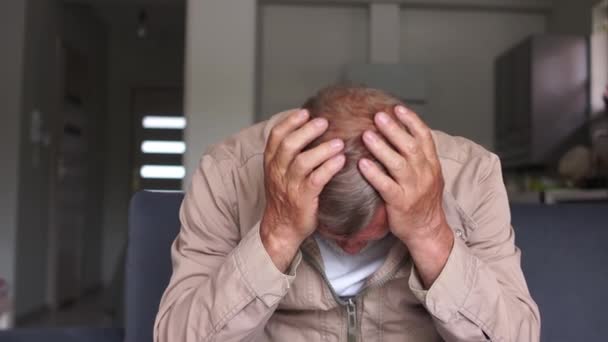 İşsizlik ve ekonomik kriz sorunları. Üzgün, gri saçlı bir adam kanepede oturur ve elleriyle yüzünü kapatır. — Stok video