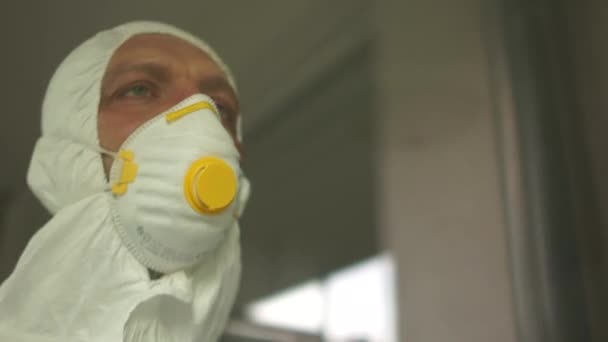 Lekarz podczas pandemii coronavirus covid-19 zdejmuje okulary i maskę ochronną, ślady twarzy są widoczne z maski, czerwone plamy. Bliski portret zmęczonego lekarza za szybą — Wideo stockowe