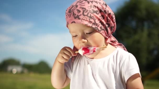 Soligt utomhusporträtt av ett barn med glass i handen. Glad barndom, småbarn äter glass, sommarsemester — Stockvideo