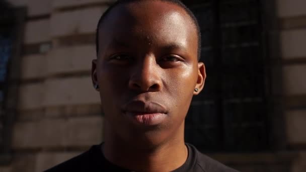 Στενή προσωπογραφία ενός νεαρού Αφροαμερικανού με σοβαρό βλέμμα. Μαύρος μαθητής που δείχνει λυπημένος στην κάμερα. Συναισθήματα ανθρώπων. Σταμάτα το ρασικμ — Αρχείο Βίντεο